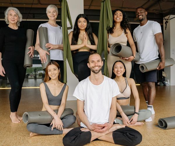 A diverse group of people smiling during a gentle yoga class.